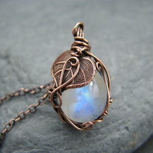 May include: A copper wire wrapped pendant necklace featuring a moonstone cabochon and a copper leaf design.