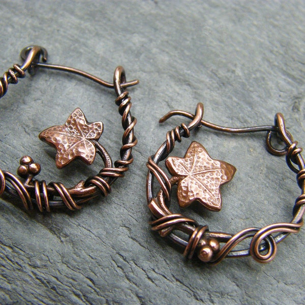 May include: A pair of copper wire earrings with a hammered copper ivy leaf design. The earrings are handmade and have a delicate, whimsical look.