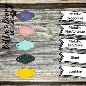 May include: Five diamond-shaped leather keychains in different colors: metallic purple, metallic pink, metallic teal, black, and yellow. The keychains are arranged vertically on a wooden surface. The text "Metallic Dragonfire", "Metallic Pink/Orange", "Metallic Teal/Lime", "Black", and "Sunshine" are written in black text on white banners next to each keychain.