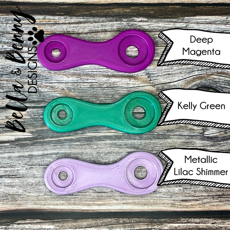 May include: Three 3D-printed chain link connectors in Deep Magenta, Kelly Green, and Metallic Lilac Shimmer. Each connector has two circular ends connected by a curved bar. The Bella & Benny Designs logo is in the upper left corner.