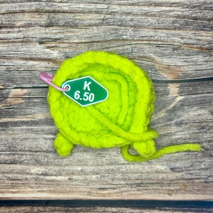 May include: A bright green ball of yarn with a green tag that says "K 6.50" attached to it.