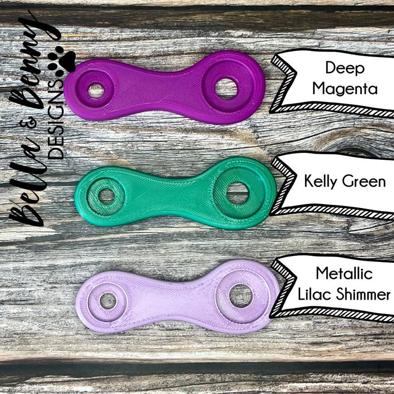 May include: Three plastic keychains in different colors: deep magenta, kelly green, and metallic lilac shimmer. Each keychain has a unique shape with two holes.