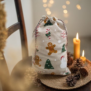Sacchetti di ornamenti natalizi per incartare i regali. Sacchetti di Natale con coulisse per dolcetti, caramelle o biscotti. Sacchetti regalo con stampa natalizia e cordino.