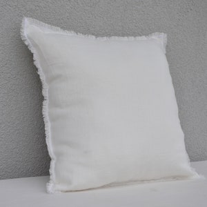 May include: A white pillow with a frayed edge. The pillow is made of a soft, textured fabric.