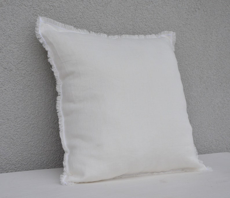 May include: A white pillow with a frayed edge. The pillow is made of a soft, textured fabric.