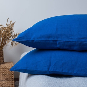 May include: Two blue linen pillowcases stacked on top of each other. The pillowcases are a deep blue color and have a slightly textured surface.