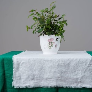 A white linen table runner with fringed edges styled for farmhouse dining table décor