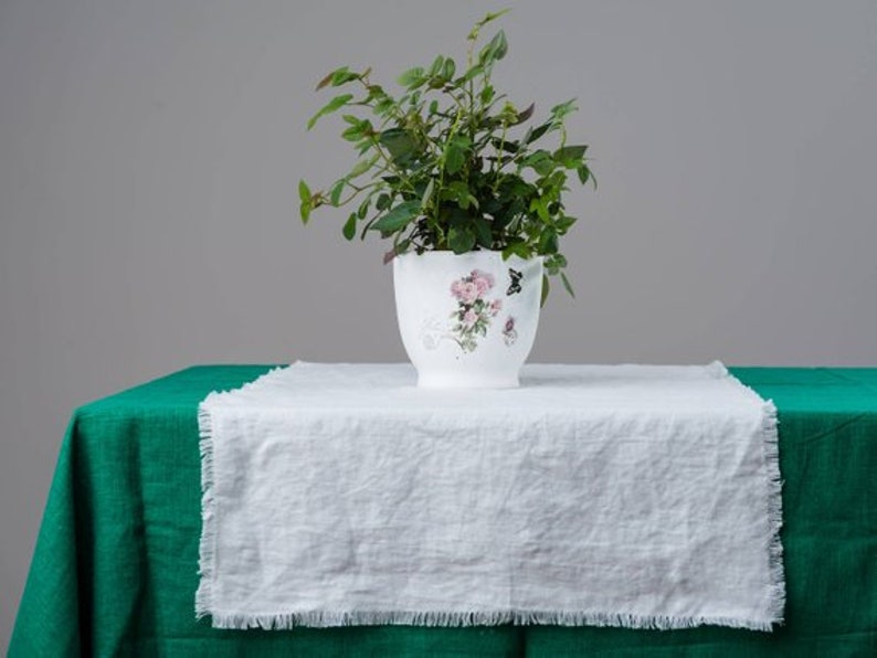 A white linen table runner with fringed edges styled for farmhouse dining table décor