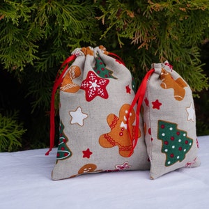 Sacchetti per dolcetti natalizi. Sacchetti per carta da regalo natalizi piccoli o grandi. Sacchetti di lino per biscotti natalizi. Sacchetti con coulisse per regali di Babbo Natale con fascia rossa.