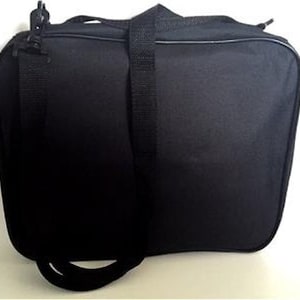 May include: Black rectangular duffel bag with a shoulder strap and a top handle. The bag has a zipper closure and a black strap that can be adjusted. The bag is made of a durable material and is suitable for travel or carrying items.