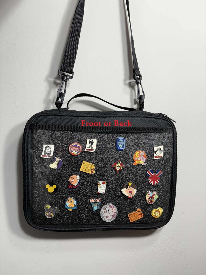 May include: Black rectangular bag with a shoulder strap, covered in colorful enamel pins. The pins feature various cartoon characters and designs. The text "Front or Back" is printed in red on the bag.