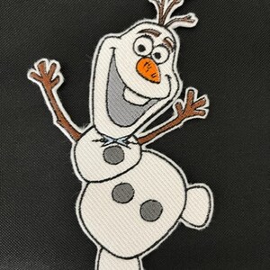 May include: Embroidered patch featuring Olaf, the cheerful snowman from Frozen. The patch has a white body with black accents, a carrot nose, and twig arms. The background is black.