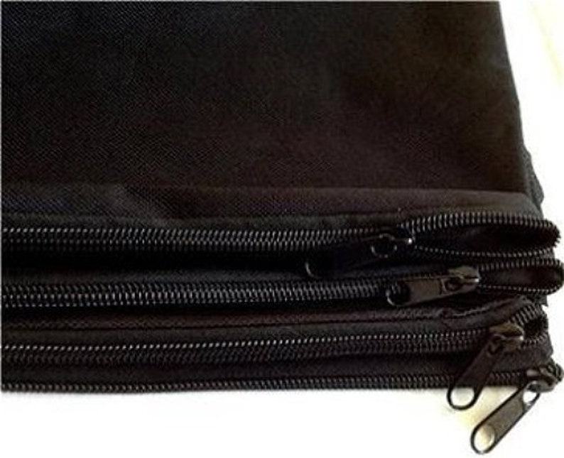 May include: Close-up of a stack of black fabric pouches with multiple zippers. The zippers are black and have metal pulls. The fabric appears to be a durable, woven material.