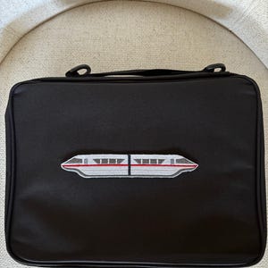 May include: A white ceramic mug with a black handle and the text "But First, Coffee" in a bold, black font. The mug is set against a blurred background, suggesting a cozy setting.