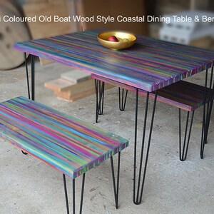 May include: Multi-coloured dining table and two benches made from reclaimed wood with a rainbow finish. The table and benches have black hairpin legs.