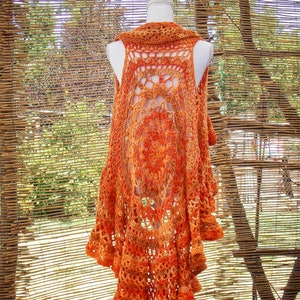May include: A crocheted vest with a lacy design in shades of orange and brown. The vest is sleeveless and has a scalloped hem.