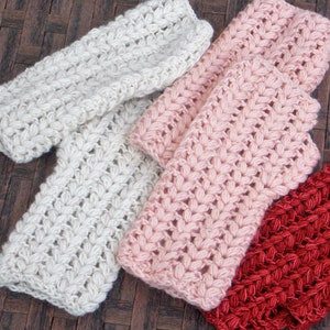 Three pairs of wrist warmers in the colors cream, pink and burnt orange