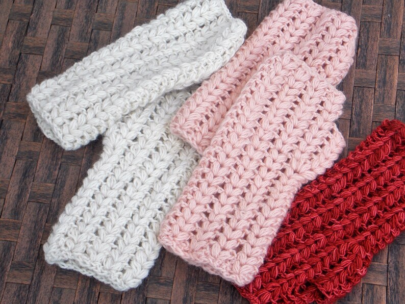 Three pairs of wrist warmers in the colors cream, pink and burnt orange