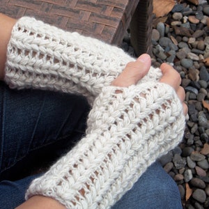 A woman wearing a set of cream colored hand/arm warmers covering her hands and wrists.