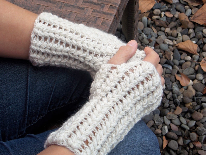 A woman wearing a set of cream colored hand/arm warmers covering her hands and wrists.