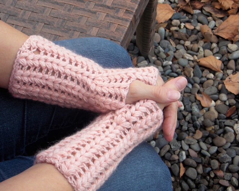 A woman with folded hands wearing pink arm/hand warmers covering her hands and wrists.
