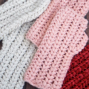 3 pairs of hand/arm warmers in the colors cream, pink and orange.