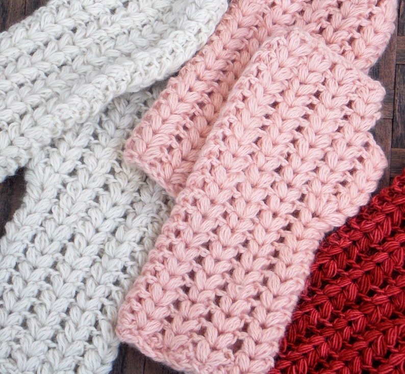 3 pairs of hand/arm warmers in the colors cream, pink and orange.