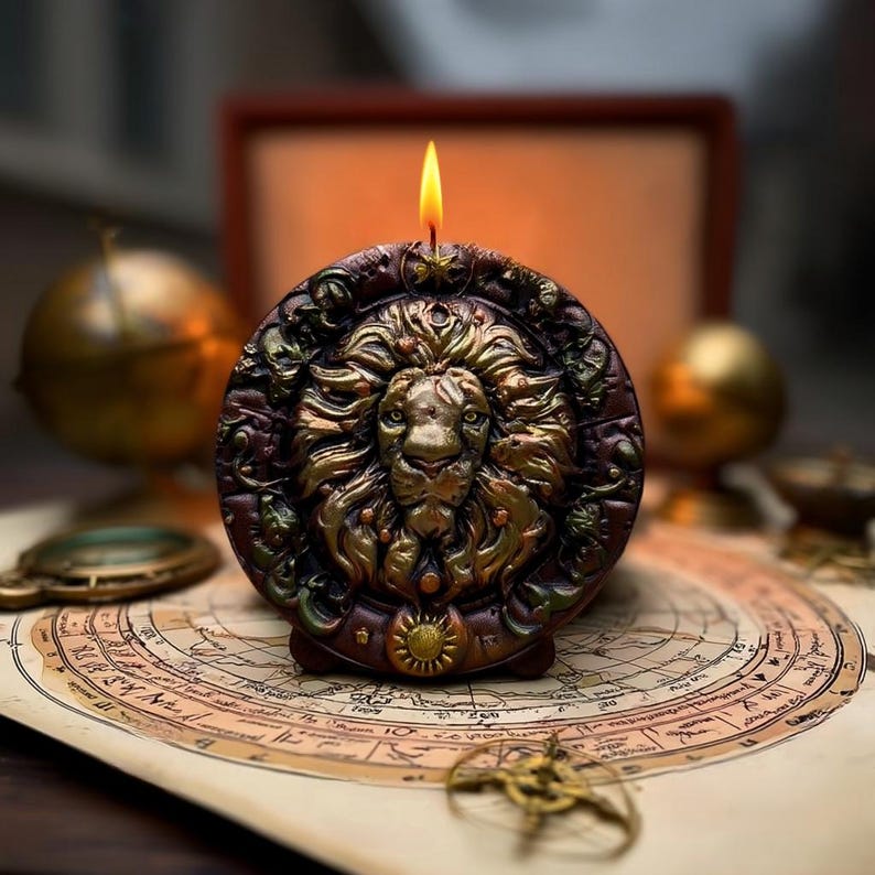 May include: A round, brown candle with a detailed lion's head design in gold. The candle is lit, with a yellow flame. The candle sits on a map, with a globe and other decorative items in the background. The candle is approximately 4 inches in diameter.