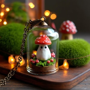 Può includere: Una collana con ciondolo a forma di fungo stravagante. Il ciondolo presenta un fungo in miniatura con un cappello rosso e bianco, racchiuso in una cupola di vetro. Il fungo poggia su un letto di muschio verde, con piccoli funghi rossi intorno. La catena è color bronzo.