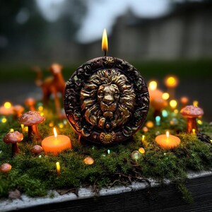 May include: A lit candle with a lion's head design, surrounded by small orange candles, mushrooms, and moss. The candle has a gold lion's head on a dark brown background. The scene is set outdoors with a blurred background.