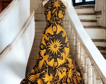 May include: A black halter dress with a gold embroidered design of birds and flowers. The dress is on a white staircase.