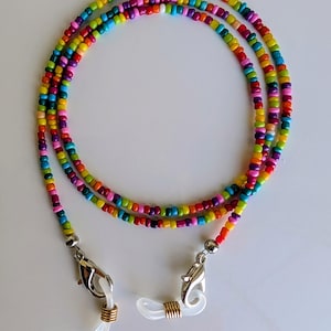 Puede incluir: Una cadena para gafas hecha de peque&ntilde;as cuentas de vidrio multicolores en tonos rojo, naranja, amarillo, verde, azul y morado. La cadena incluye cierres de mosquet&oacute;n plateados y bucles de silicona blanca con espirales de color dorado.