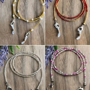Puede incluir: Cuatro cadenas para gafas hechas de cuentas con varias combinaciones de colores. Una es dorada con cuentas blancas, una es roja y dorada, una es plateada transparente y una es rosa, blanca y transparente. Cada cadena incluye cierres de mosquet&oacute;n.