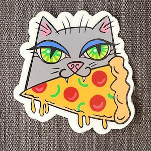 Może przedstawiać: Szary kot z zielonymi oczami i niebieskim cieniem do powiek je kawałek pizzy z pepperoni, zielonymi paprykami i serem. Pizza kapie serem i sosem.