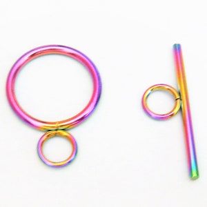May include: A rainbow-colored metal toggle clasp with a round ring and a straight bar. The clasp is used for jewelry making.