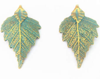 May include: A pair of gold and green leaf-shaped earrings. The leaves have a textured surface and a detailed vein pattern.