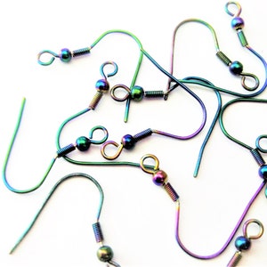May include: A close-up of a group of rainbow-colored earring hooks. The hooks are made of metal and have a small ball at the end. The hooks are arranged in a random pattern.