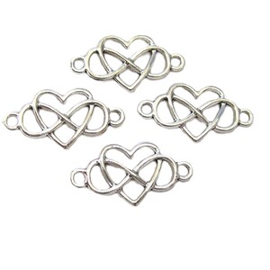 May include: Four silver-toned metal charms. Each charm features a heart intertwined with an infinity symbol, with small loops on each end for attachment. The charms are displayed against a white background.