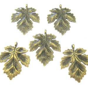 May include: Five bronze-colored leaf charms with a loop at the top for hanging. The leaves have detailed veining and a slightly aged appearance. These decorative charms are ideal for jewelry making or craft projects.