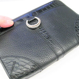 May include: Black leather clutch with a crocodile embossed pattern and a silver ring closure.