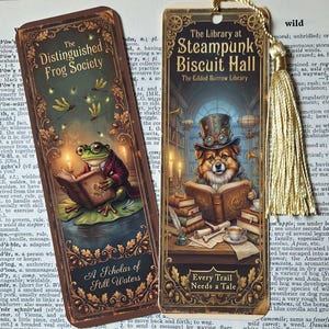 May include: Two rectangular bookmarks with ornate gold borders. The left bookmark features a frog reading a book with the text The Distinguished Frog Society and A Scholar of Still Waters. The right bookmark shows a dog in a top hat reading with the text The Library at Steampunk Biscuit Hall and Every Trail Needs a Tale, finished with a gold tassel.