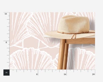 May include: A light pink wallpaper with a white shell pattern. A straw hat is sitting on a wooden table in front of the wallpaper.