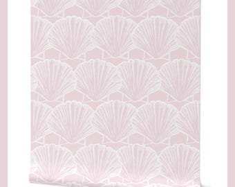 May include: A roll of wallpaper featuring a repeating pattern of white scallop shells on a light pink background. The text "Classic Scallop Shells Bermuda Pink" is at the top. The designer's name, "Lisa Kling Design", is at the bottom.