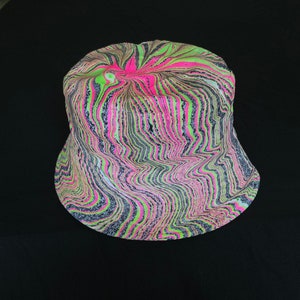 May include: A black, green, and pink bucket hat with a swirling, marbled pattern.