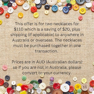 May include: A variety of colourful buttons in different sizes and shades, such as red, yellow, blue, and white, are scattered on a textured, tan background. The image contains text about a necklace offer.