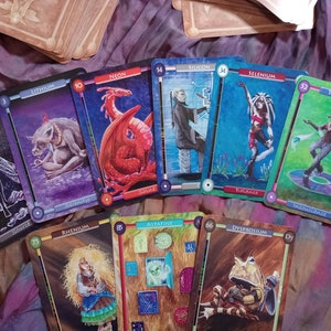 Pu&ograve; includere: Un set di carte da gioco colorate con illustrazioni di creature mitiche ed elementi. Le carte sono numerate con i numeri atomici di diversi elementi, come l'idrogeno, il neon, il litio, il silicio, il selenio, il tellurio, il renio, l'astato e il disprosio.