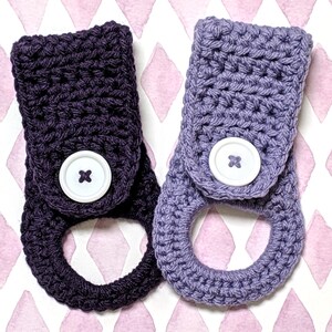 May include: Two crocheted towel holders with a button closure. One is dark purple and the other is light purple.