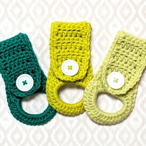 May include: Three crocheted dish towels in green, yellow, and light green with white buttons. Each towel has a loop for hanging.