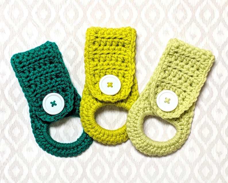May include: Three crocheted dish towels in green, yellow, and light green with white buttons. Each towel has a loop for hanging.