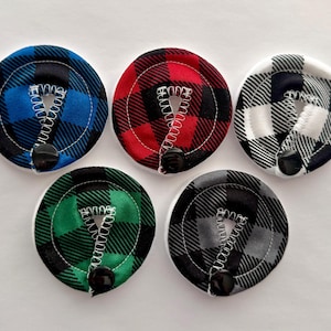 May include: Five round fabric circles with a black and white checkered pattern. Each circle has a different colored center: blue, red, white, green, and gray. The circles have a black button in the center.